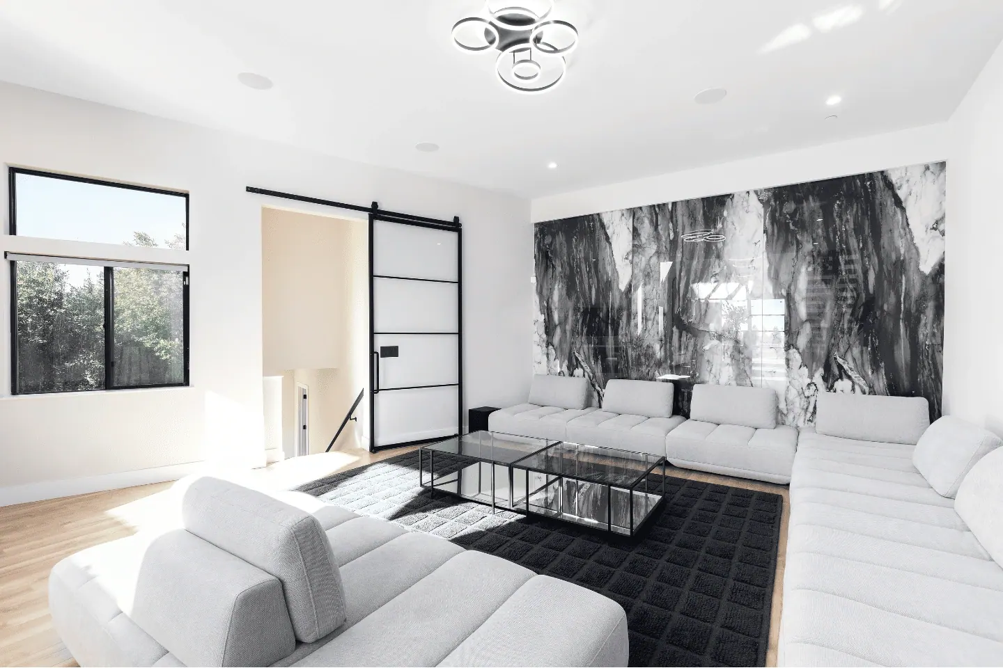 Light-filled Aziz Construction living room with white sofas and a marble feature wall
